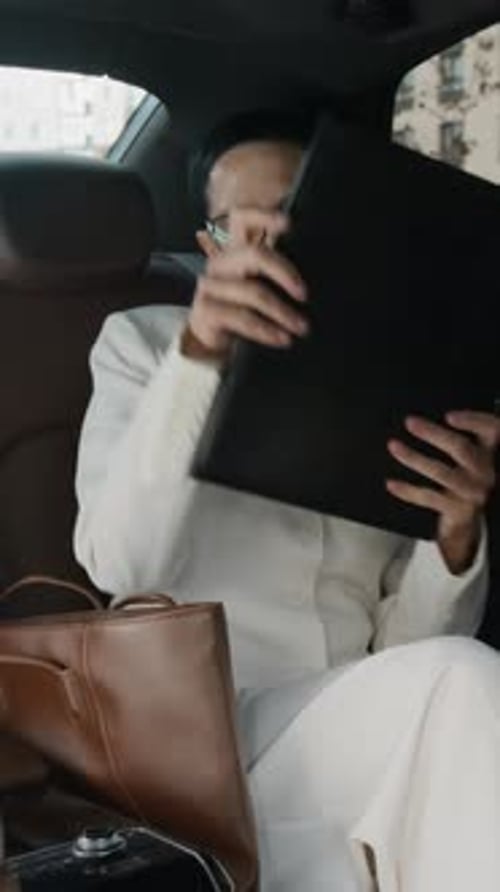 Businesswoman in Car Reviews Document in Briefcase