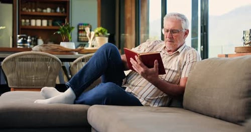 Senior Man Relaxing on Couch and Reading Book