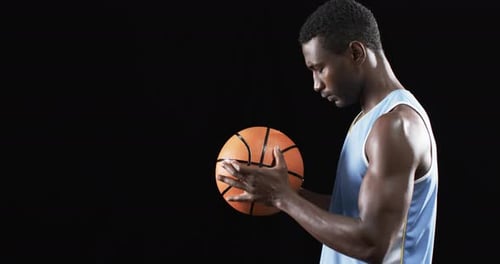 Muscular Man Holding Basketball in Dark Studio