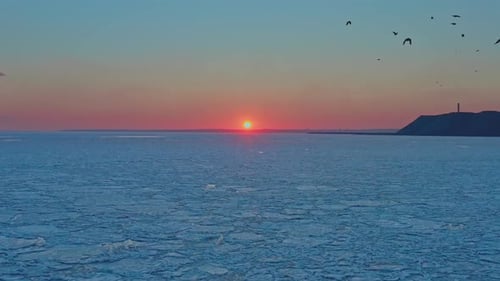 Vue aérienne du coucher de soleil sur la mer gelée en hiver Un drone vole vers l'avant vers le lever du soleil et Horizon Copter