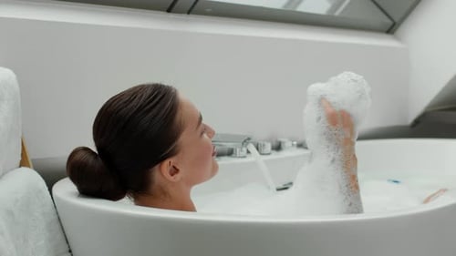 Woman relaxing in luxurious bubble bath at home