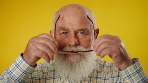 Senior Man Puts on Reading Glasses, Close Up