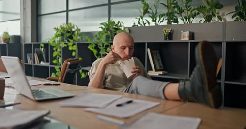 A Bald Office Worker Relaxes at the Meeting Table Enjoying His Pasta During a Break Before Returning