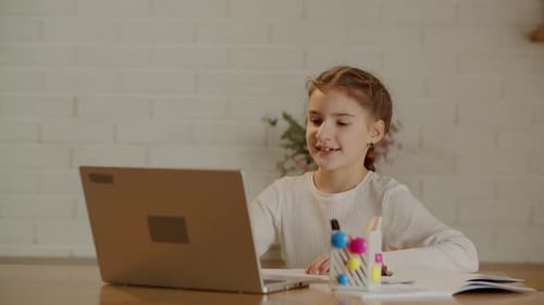 A Girl with Pigtails is Greets the Teacher and Starts the Lesson at a Laptop Elementary School
