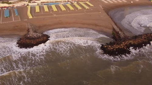 Aerial top down view of the breakwater at the coast, powerful water waves of the Ocean reaching sand