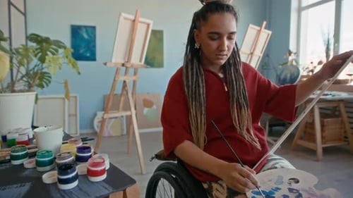 Dedicated Female Artist in Wheelchair Painting on Canvas in Mdern Studio
