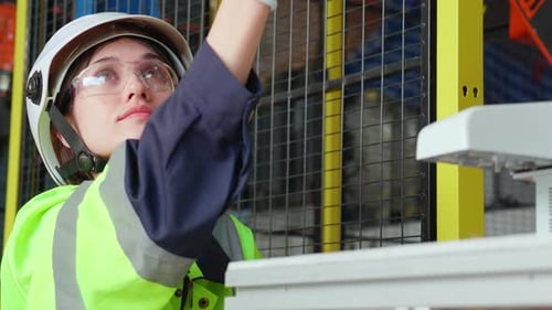 Jeune ingénieure vérifiant et entretenant la technologie des bras robotiques de la machine dans une usine industrielle.