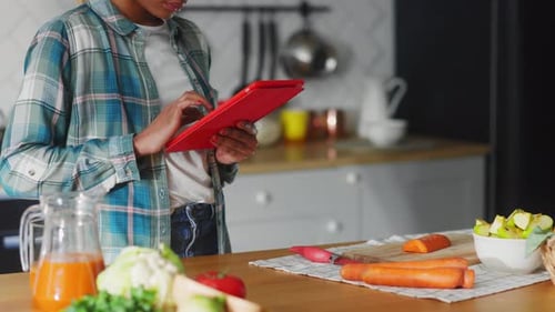 Woman Uses Tablet Near Vegetables in Kitchen