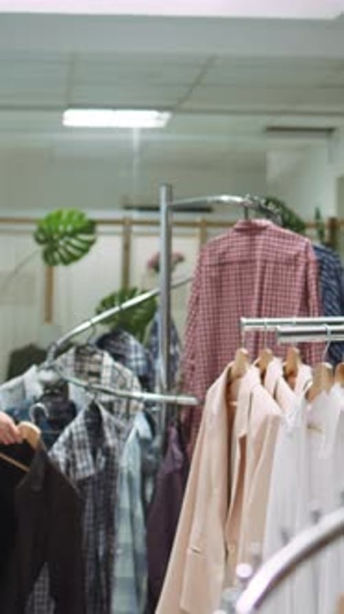 Vertical Video Designer Boutique Assistant Arranging a Vibrant Selection of Garments on Racks
