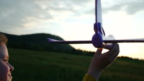 Close up of happy pretty little girl playing with toy airplane on background sky during sunset