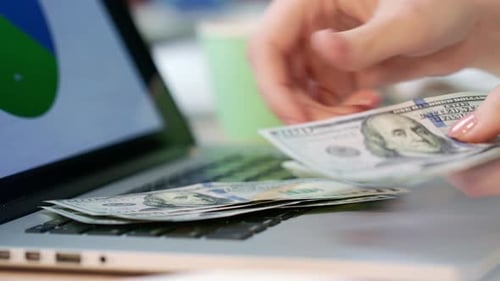 Counting Money Next to Laptop Computer with Graphics