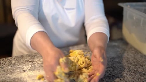 Person Kneading Yellow Dough on Marble Countertop