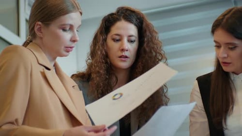 Medium close up shot of busy group of three females working finding solutions.