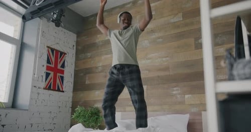 Young Adult Dancing Energetically on a Bed