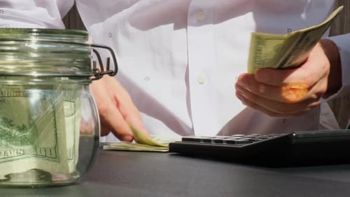 Erfahrener Händler zeigt digitale Bitcoin-Münze Gold, nachdem er Einkommensbanknoten in Dollar-Bargeld gezählt hat