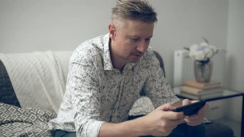Man Sitting on Couch Using a Mobile Phone