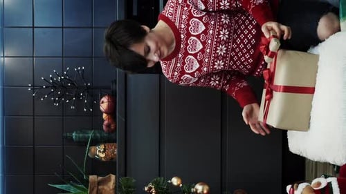 Woman Arranging Christmas Gifts by Tree