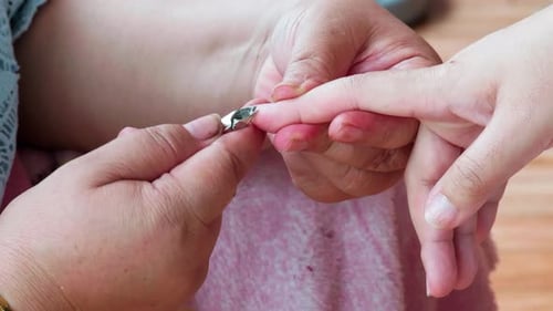 Cosmetologist beautician is making manicure in cosmetology clinic using nippers