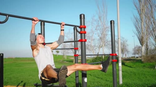 Athlete Man Does Pull Ups on Horizontal Bar Outdoors