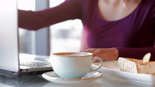 Woman Works on Laptop with Coffee and Cake