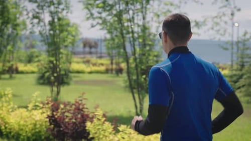 View From the Back A Man in Sportswear Runs Through a Landscaped City Park Public Urban Spaces for