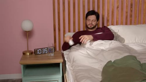 Sleepless Middle Aged Man Taking Sleeping Pills in Bed Before Sleep