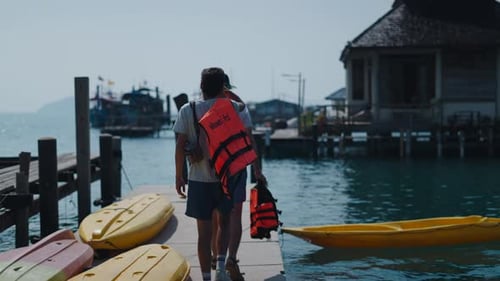 Two Friends Prepare for a Kayaking Adventure on a Lakeside Dock