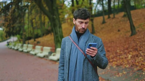 Portrait Young Handsome Man Stand with Dog in Autumn Park Holding Use Phone Typing on Smartphone