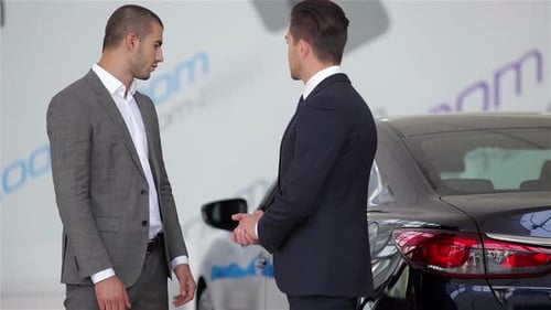 Men in Suits Shake Hands in Car Showroom