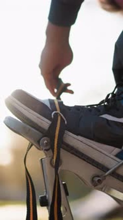 Closeup de alças de palafitas ajustáveis à mão masculina com fundo iluminado pelo sol e tênis