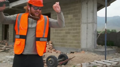 Happy engineer contractor dancing on construction site having fun in good mood.