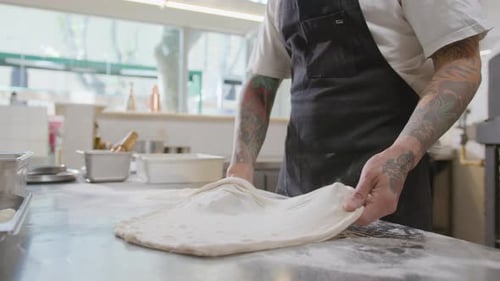 Chef stretches pizza dough in kitchen