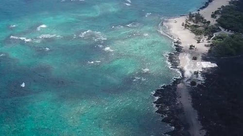 Drone aerial black sand beach pan down blue water