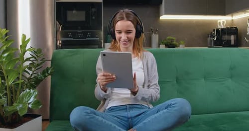 Mujer feliz y sonriente usando una tableta digital navegando, transmitiendo y viendo videos en línea en casa