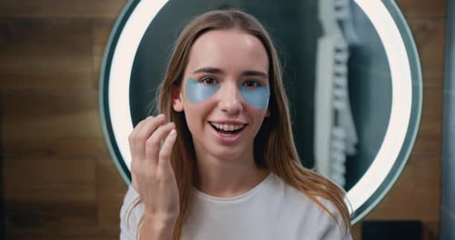 Young Woman Applying Eye Patches in Bathroom