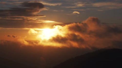 Golden Sunset Over Mountain Range with Glowing Clouds