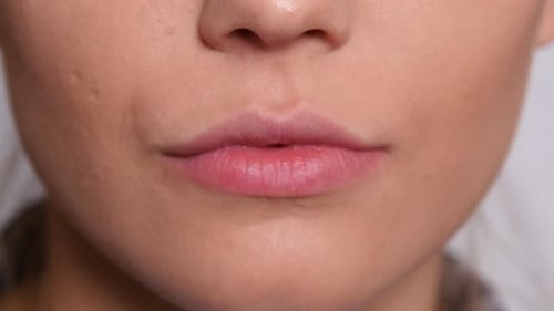 Extreme close up of a young woman's smiling mouth in a studio headshot