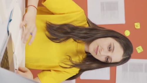Young Woman Writes in Notebook at Her Desk