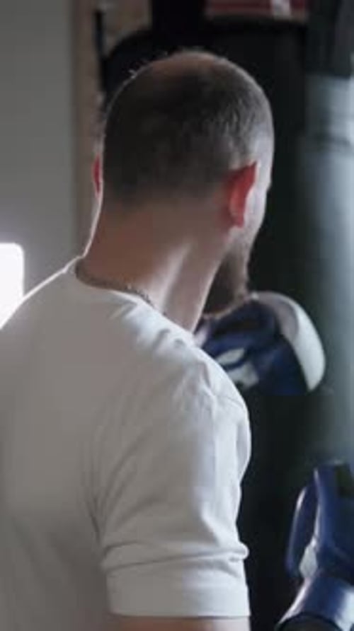 Male fighter in boxing gloves training in gym before fight. Vertical shot.