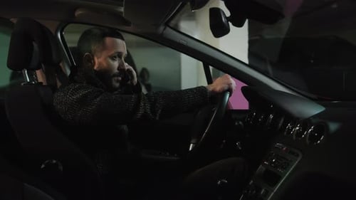 Adult Man Talks on Phone in Car at Night