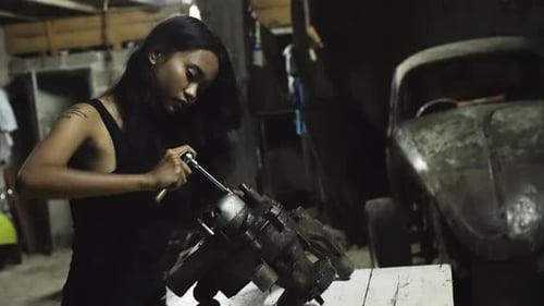 A young Asian female mechanic working in an automotive garage.