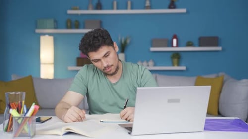 Young Adult Studying At Home With Laptop and Book