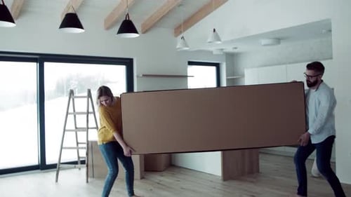 Couple moving boxes into new home interior daytime