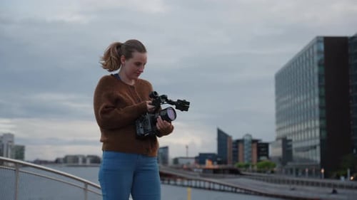 Woman Adjusting Camera in Modern Urban Setting
