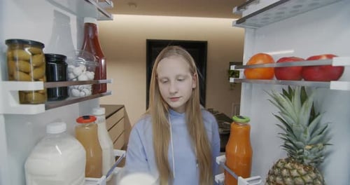 Girl Drinks Milk from Refrigerator Interior View