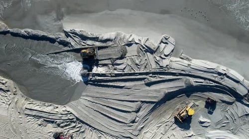 Drone shot of beach nourishment, or adding sand or sediment to beaches to combat erosion, with water