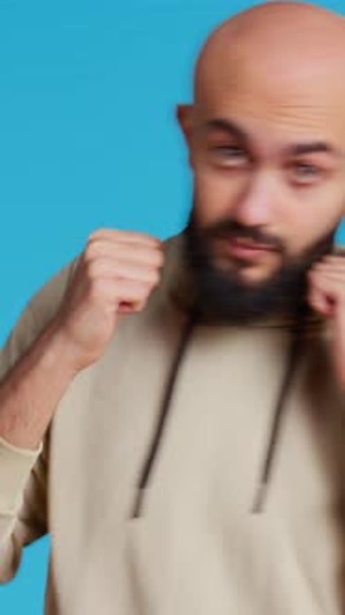 Man Practices Punching Posing Against Blue Backdrop