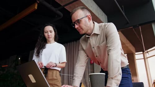 Diverse colleagues stand near the desk looking at the computer screen.