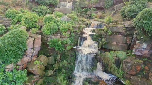 Yorkshire moors host an alluring waterfall. Aerial view reveals water streaming over rocks, falling