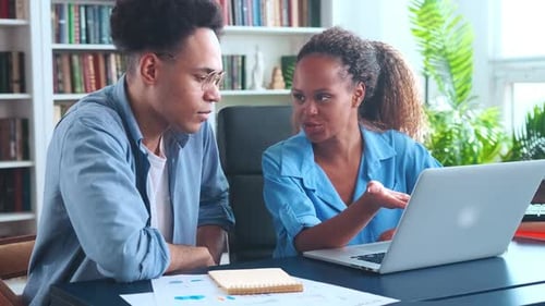 Young Colleagues African American Woman and Man Sits at Table in Office